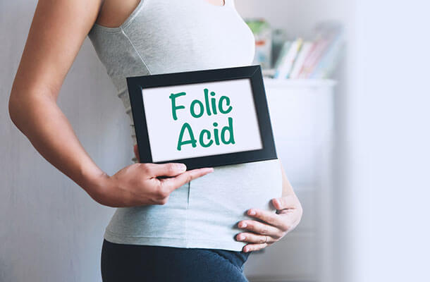 folic-acidと書かれたボードを抱えた妊婦